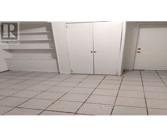 A white tiled room with a white door and a white shelf.