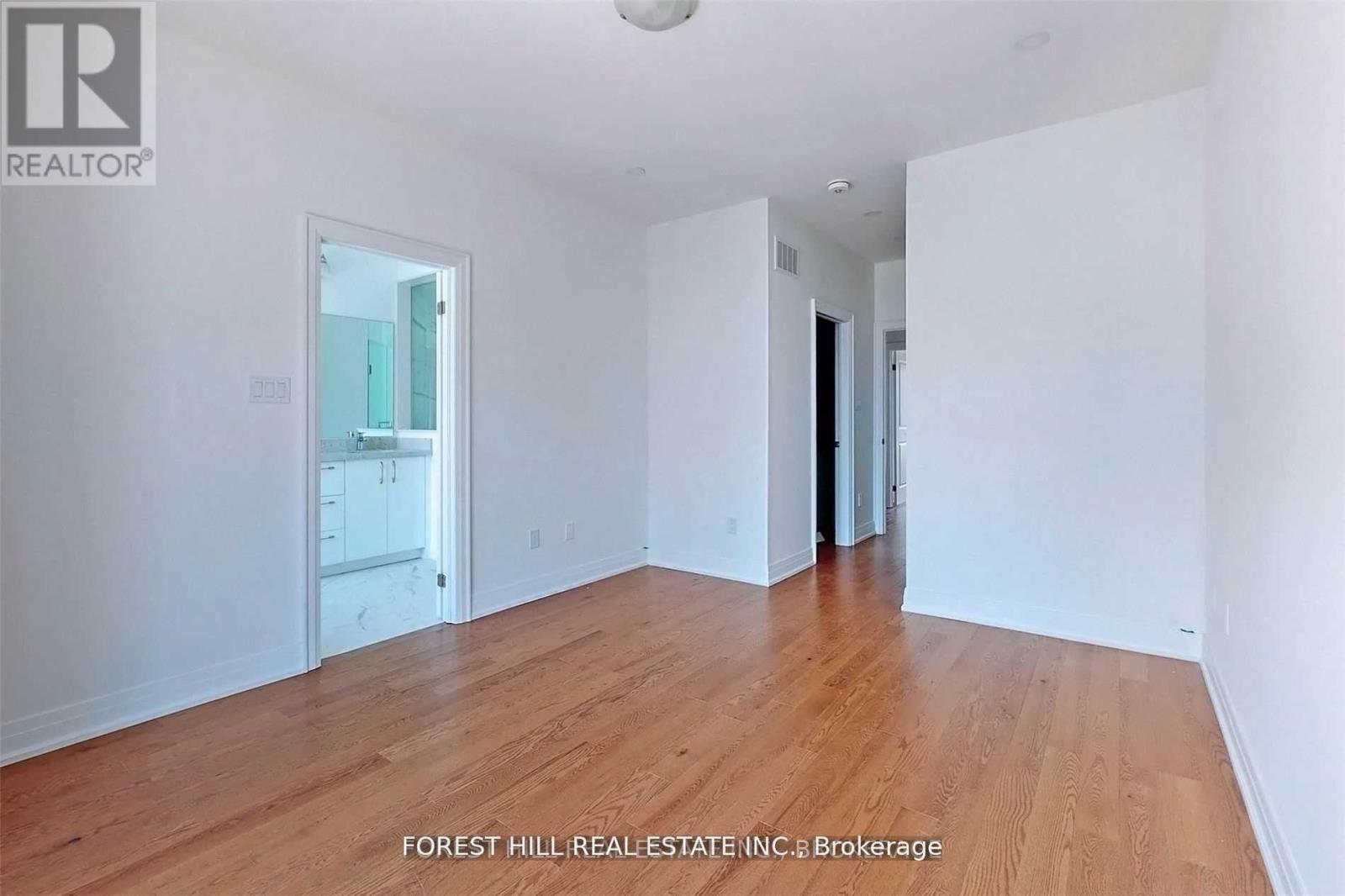 A spacious room with wooden flooring and white walls.