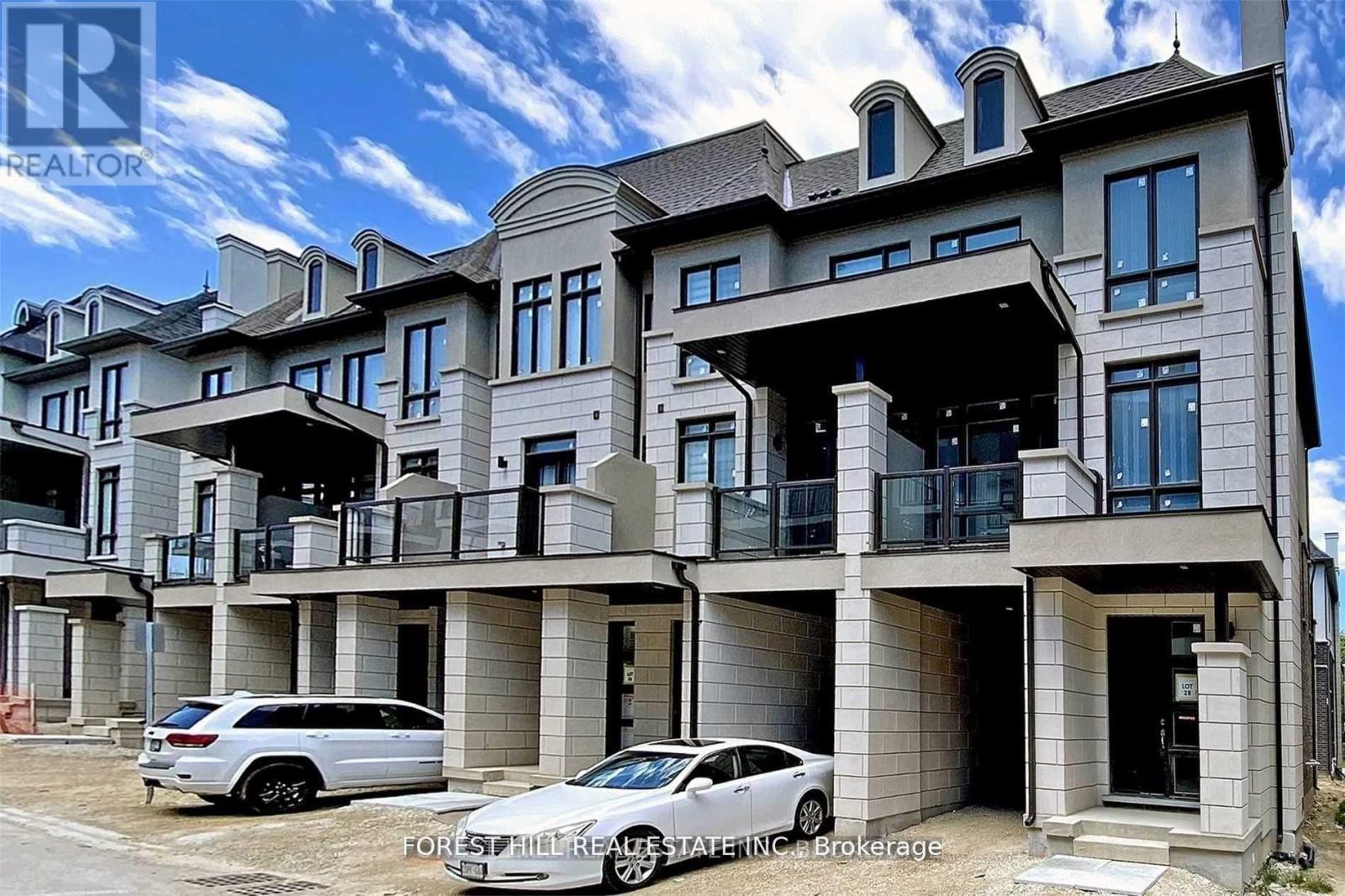 A large, modern house with a car parked in front.