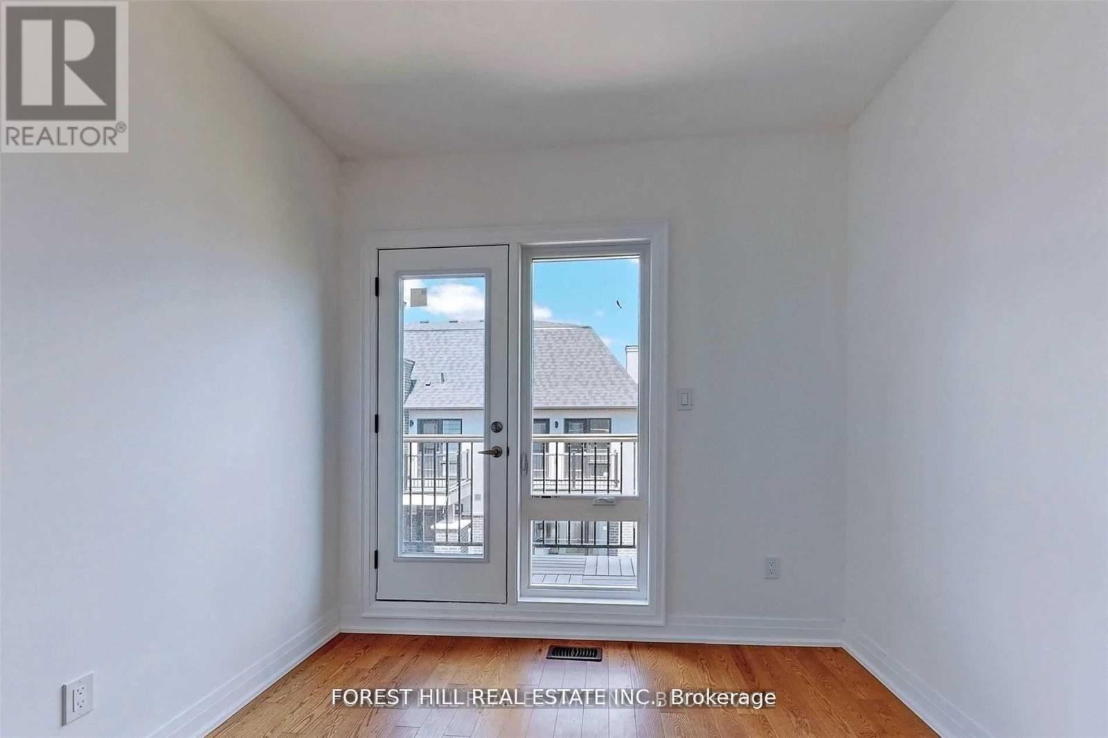A room with a white wall and a door with a view of a building outside.