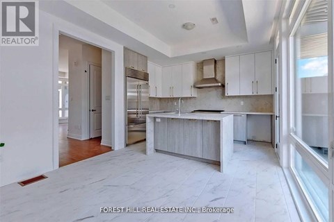 A kitchen with white cabinets and a marble floor.