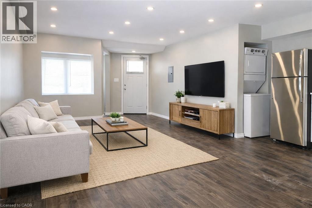 A modern living room with a grey sofa, a wooden coffee table, a flat screen TV, and a refrigerator.