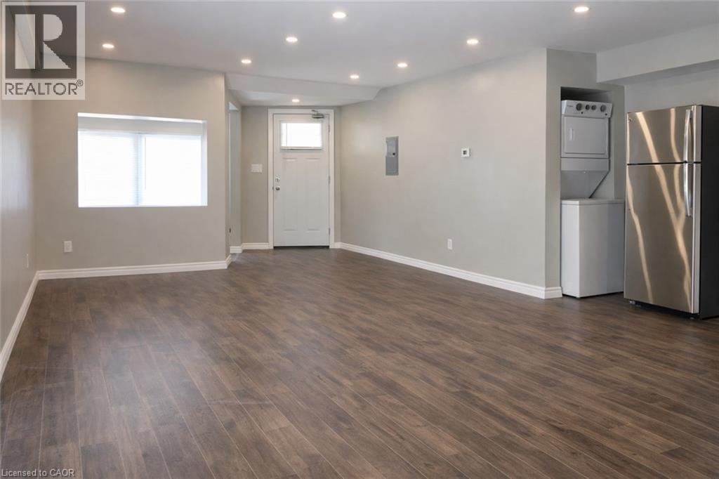 A spacious room with wood flooring and a refrigerator in the corner.