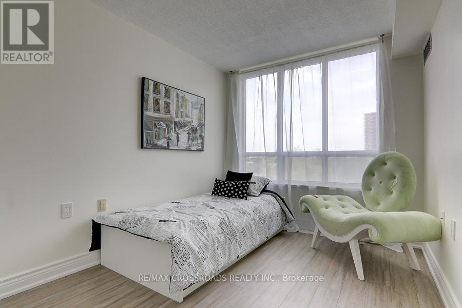 A bedroom with a bed, chair, and picture on the wall.