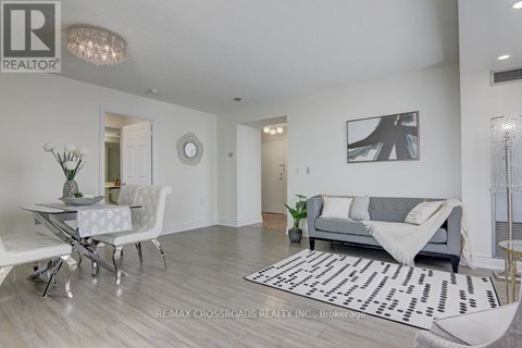 A living room with a grey couch and a white dining table.