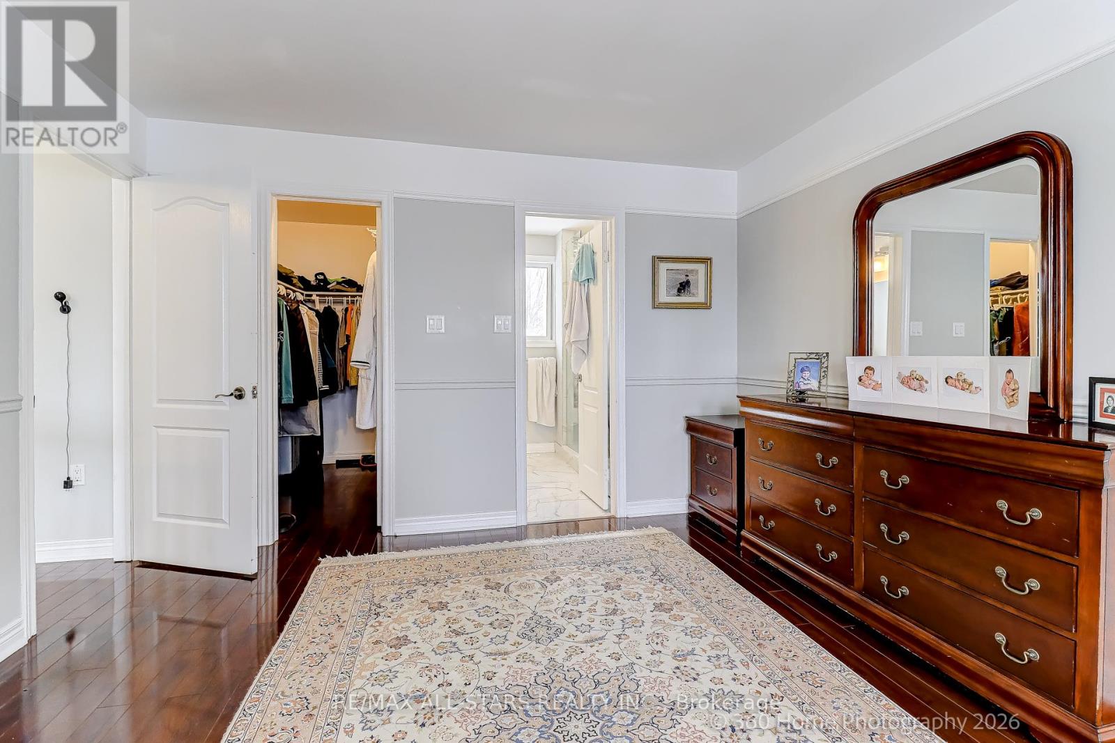 A bedroom with a large rug and a wooden dresser.
