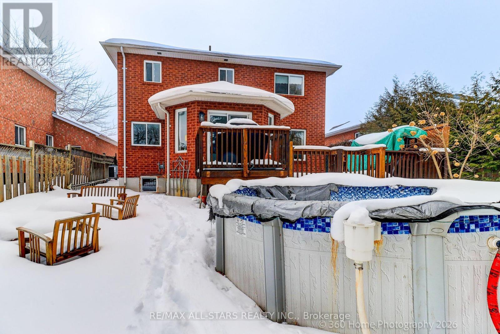 A red brick house with a pool in the backyard covered in snow.