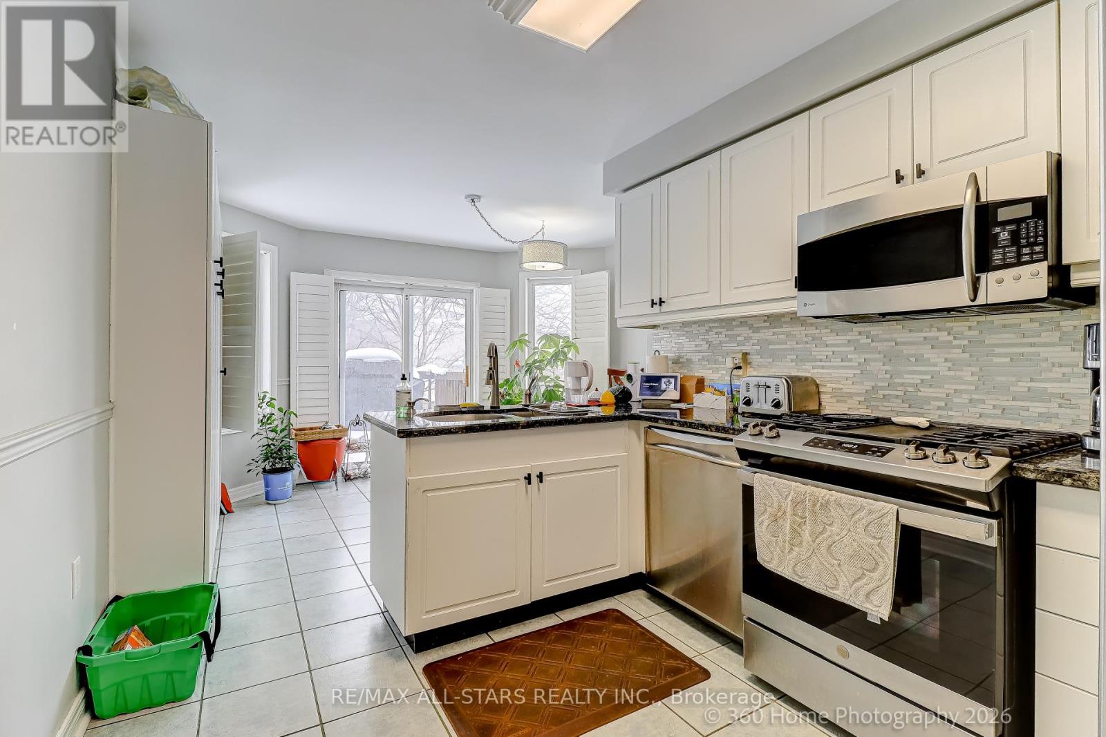 A kitchen with white cabinets and black appliances.