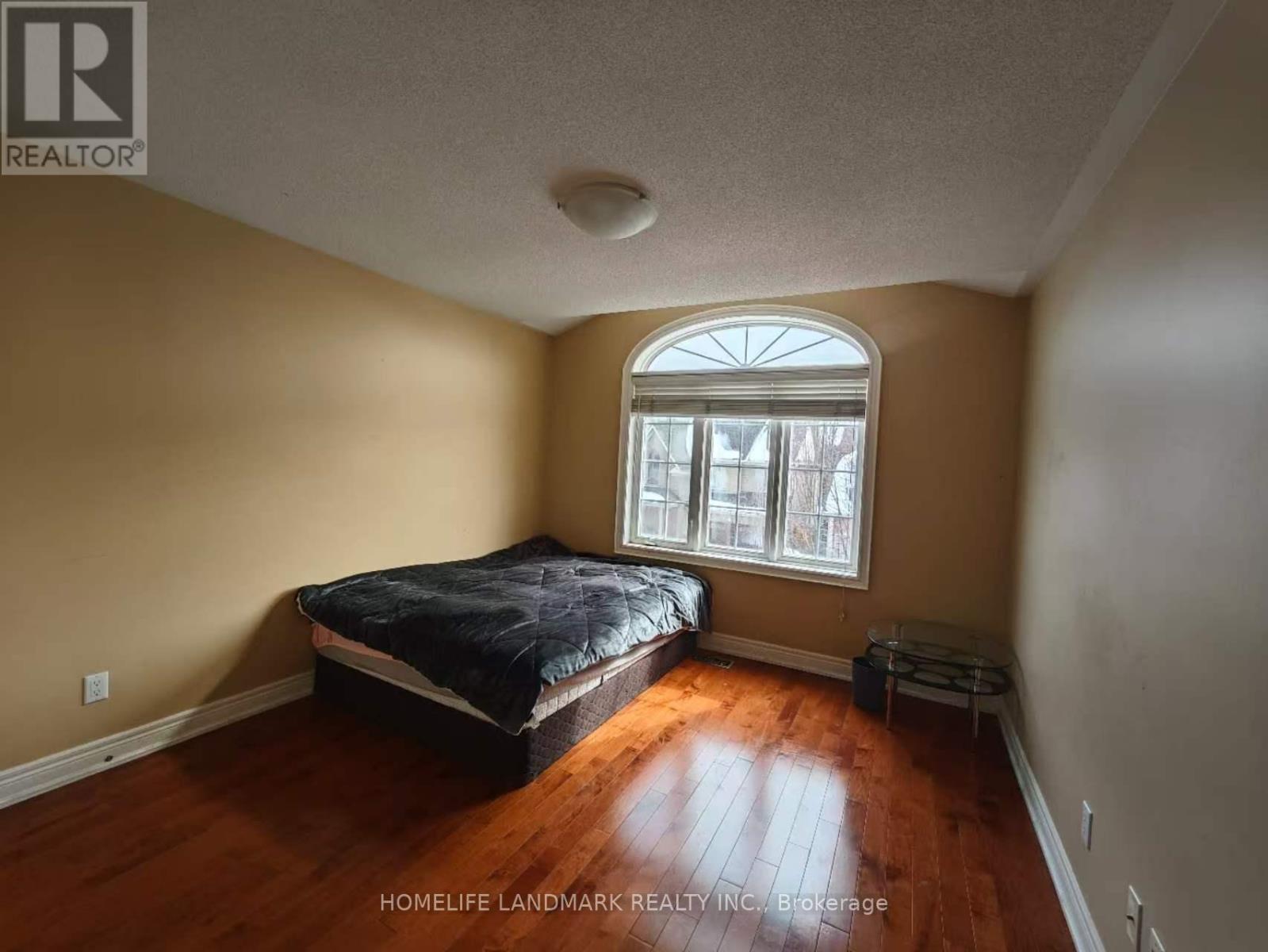 A bedroom with a bed, a window, and a wooden floor.