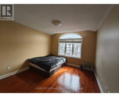 A bedroom with a bed, a window, and a wooden floor.