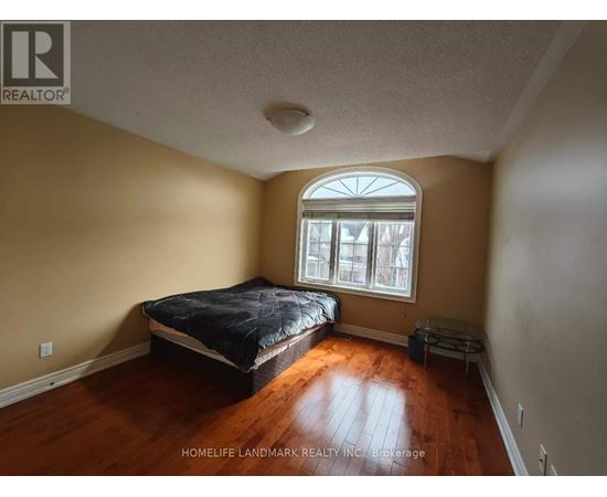 A bedroom with a bed, a window, and a wooden floor.