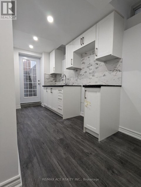 A modern kitchen with white cabinets and a marble backsplash.