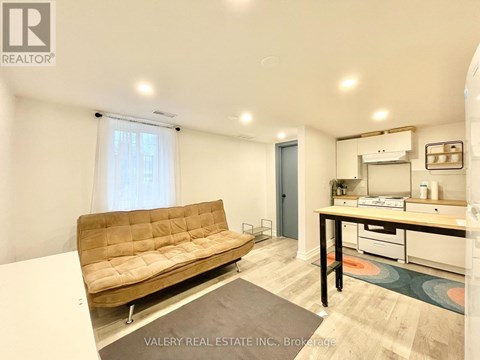 A living room with a brown couch and a small kitchenette.
