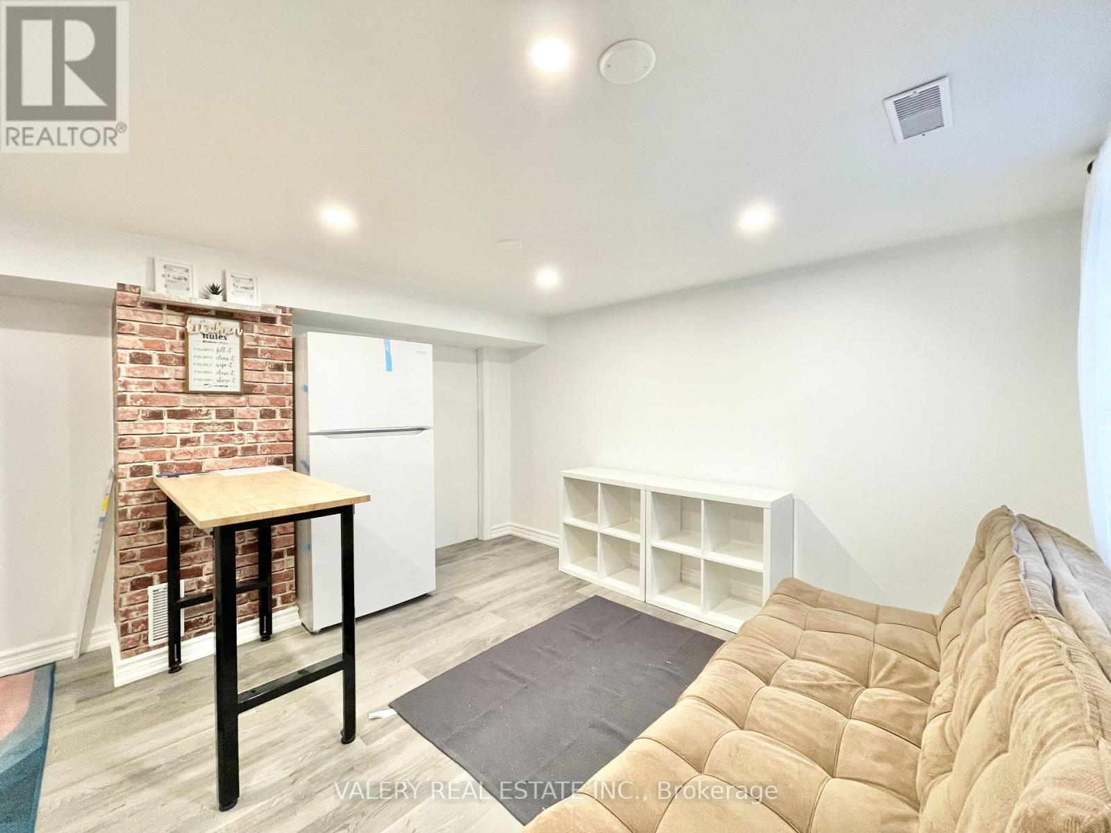A living room with a couch, a table, and a brick wall.
