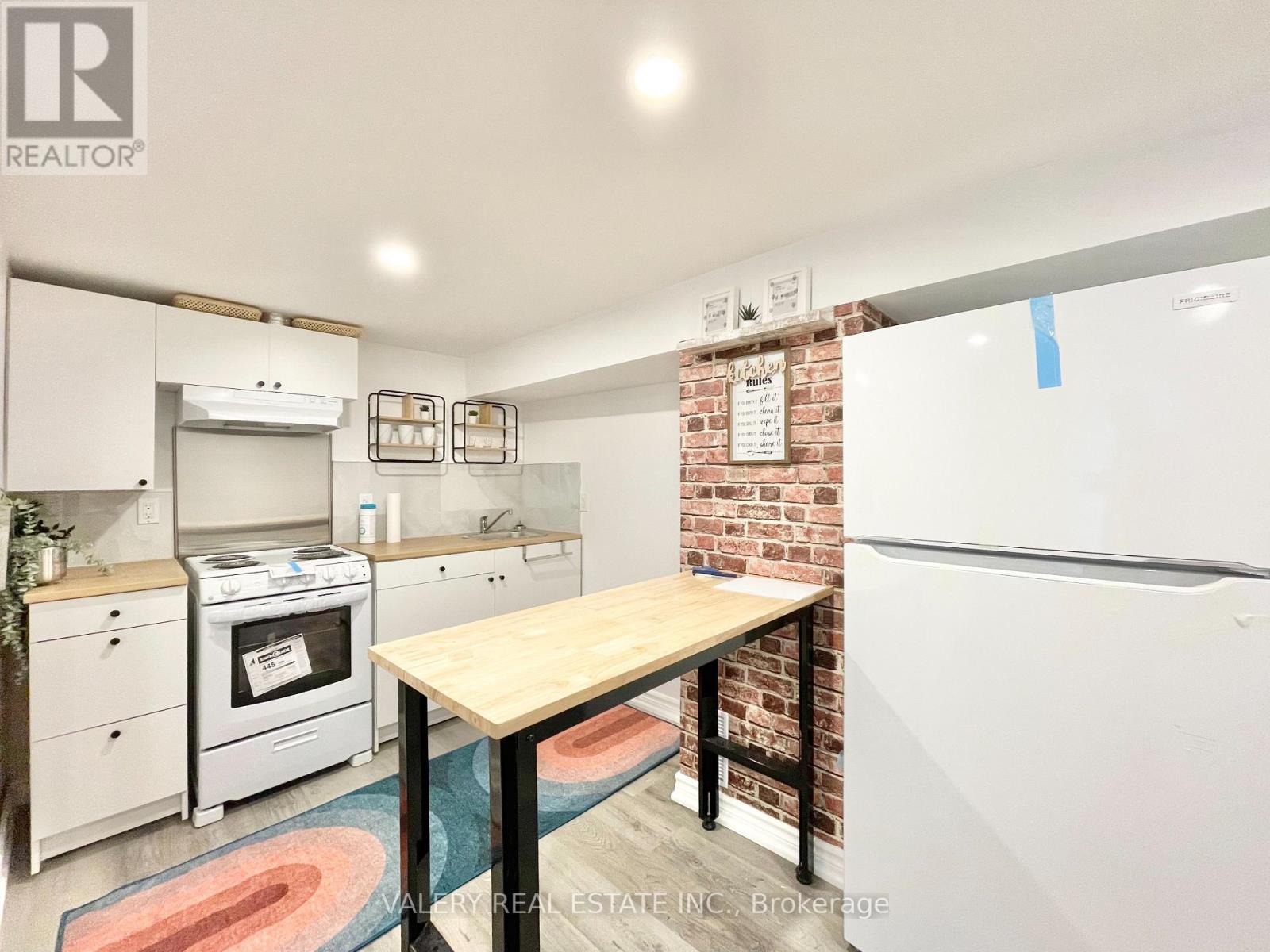 A kitchen with a brick wall and a wooden table.