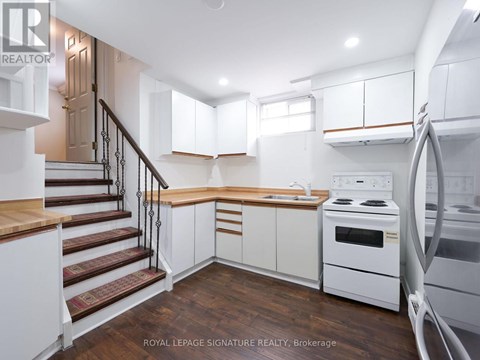 A modern kitchen with white cabinets and a wooden staircase.