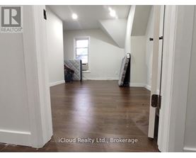 A room with white walls and wooden flooring, with a mattress and box spring in the corner.