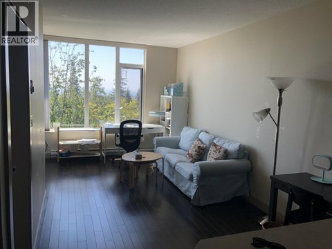 A living room with a grey couch and a black chair.