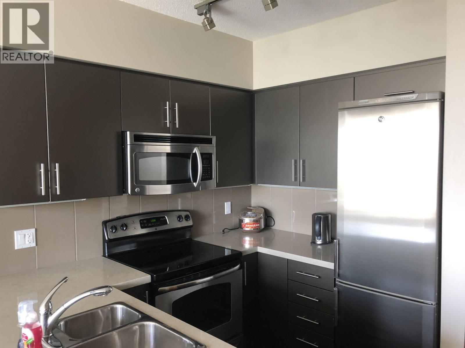 A kitchen with black cabinets and stainless steel appliances.