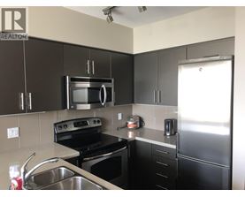 A kitchen with black cabinets and stainless steel appliances.