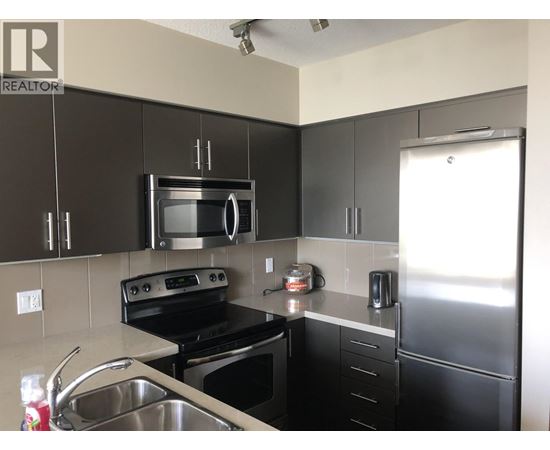 A kitchen with black cabinets and stainless steel appliances.