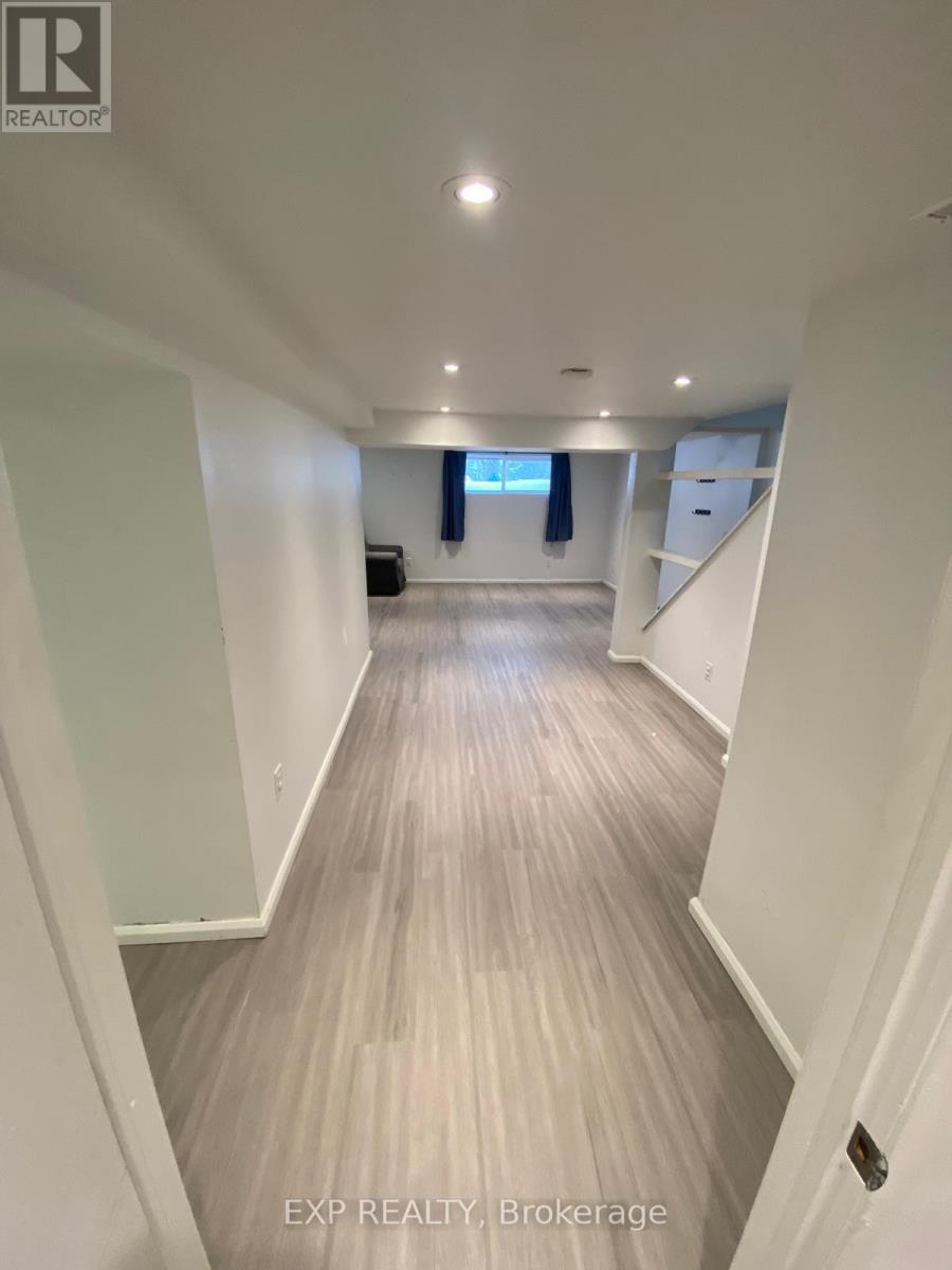 A long hallway with wood flooring and white walls.