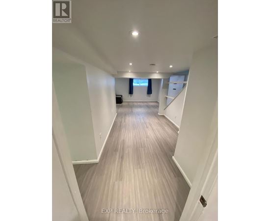 A long hallway with wood flooring and white walls.