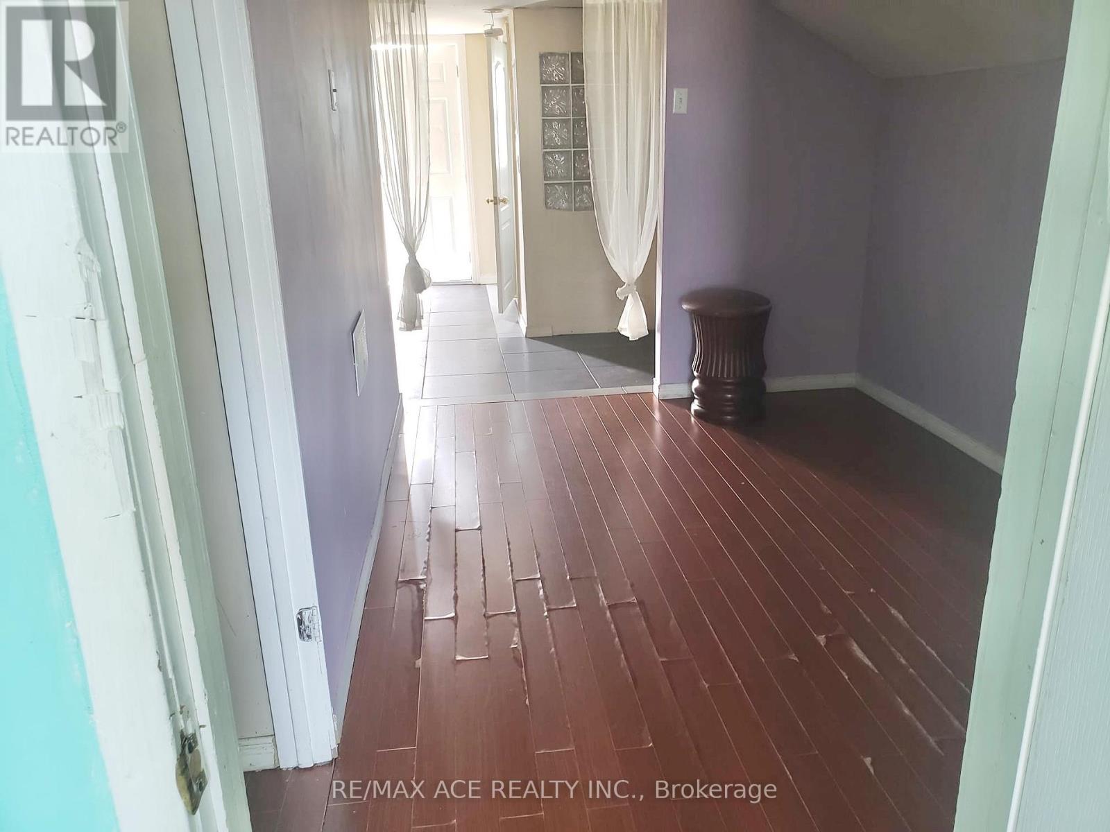 A hallway with wooden floors and white curtains.