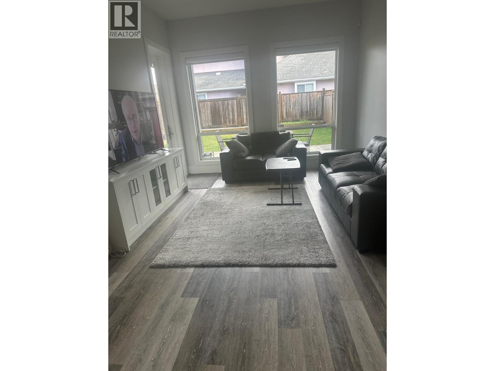 A living room with a grey rug and a black couch.