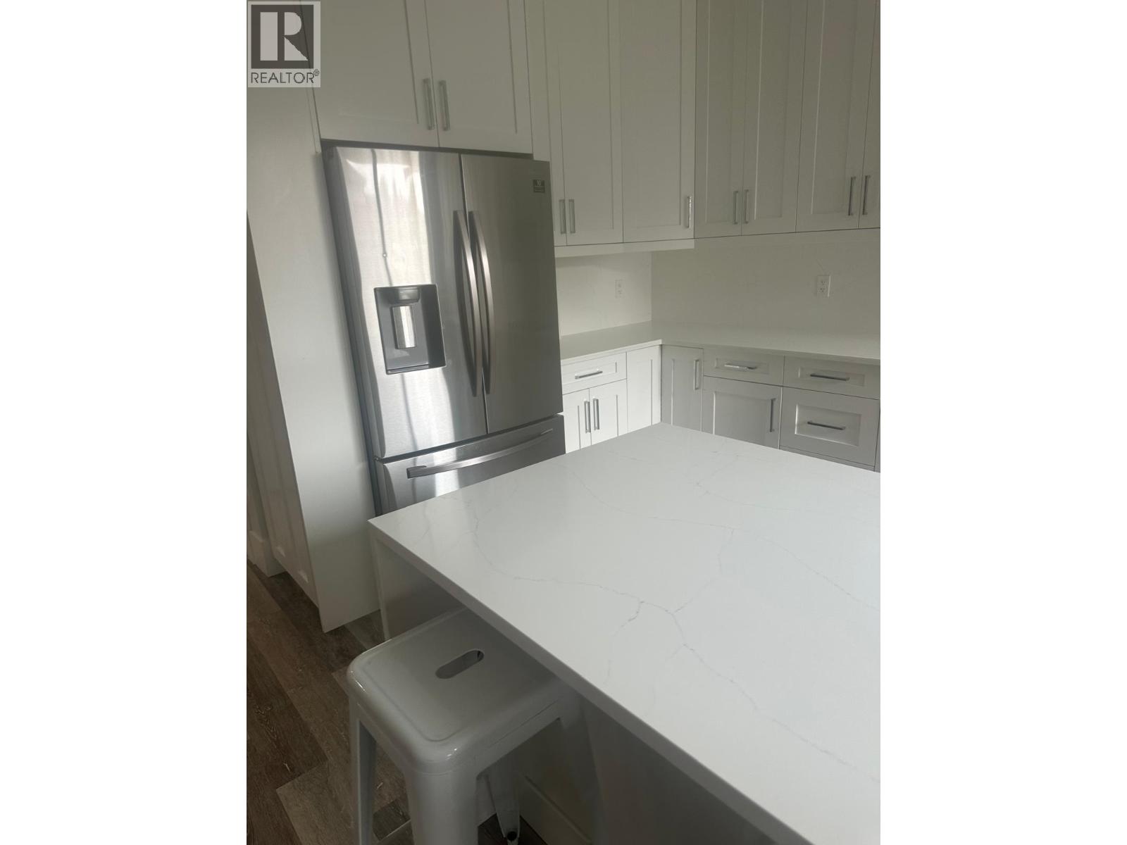 A white kitchen with a refrigerator and a counter.