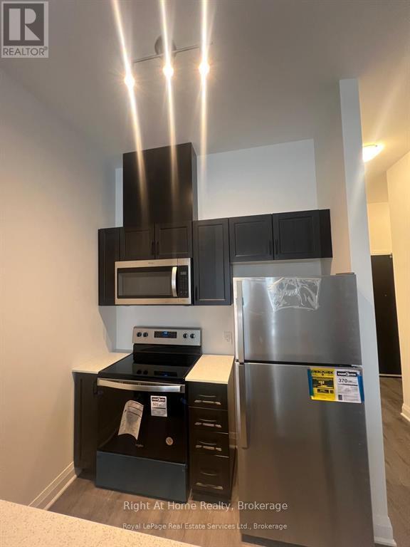 A kitchen with a stainless steel refrigerator and black cabinets.
