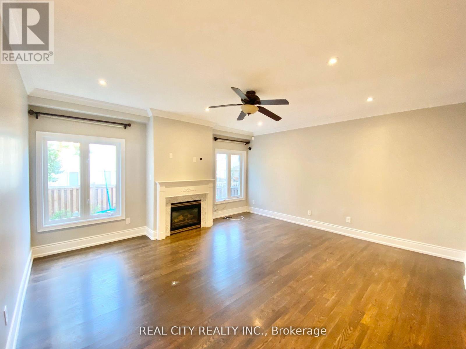 A spacious living room with wood flooring and a fireplace.