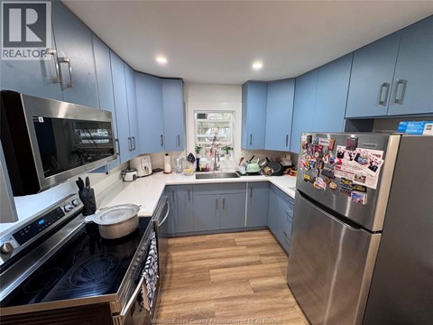 A kitchen with blue cabinets and a refrigerator covered in magnets.