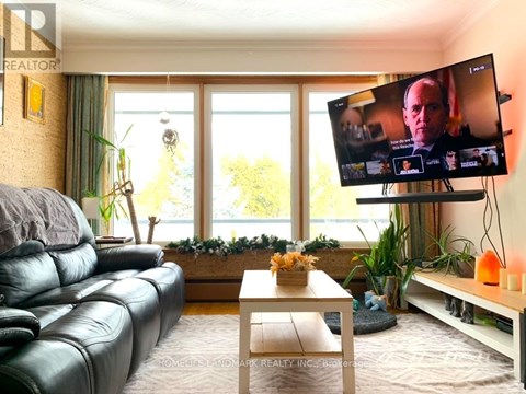 A living room with a leather couch and a television on a stand.