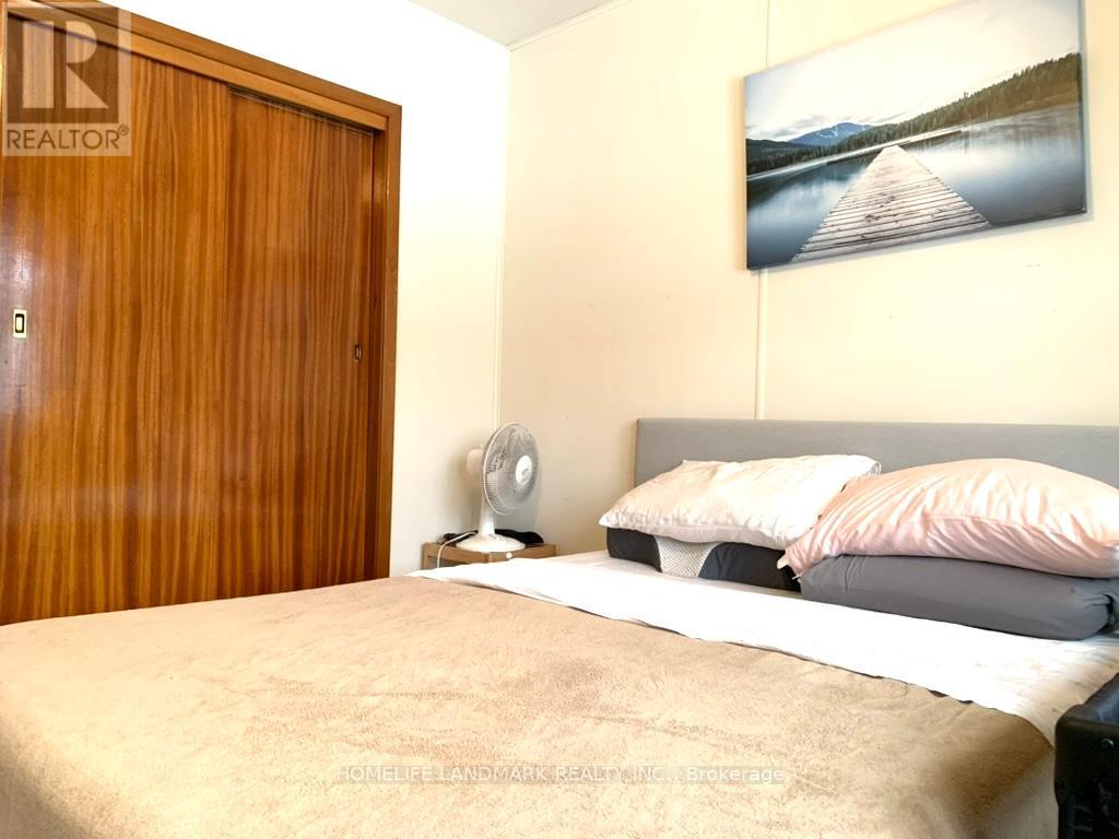 A bedroom with a bed, a fan, and a painting on the wall.