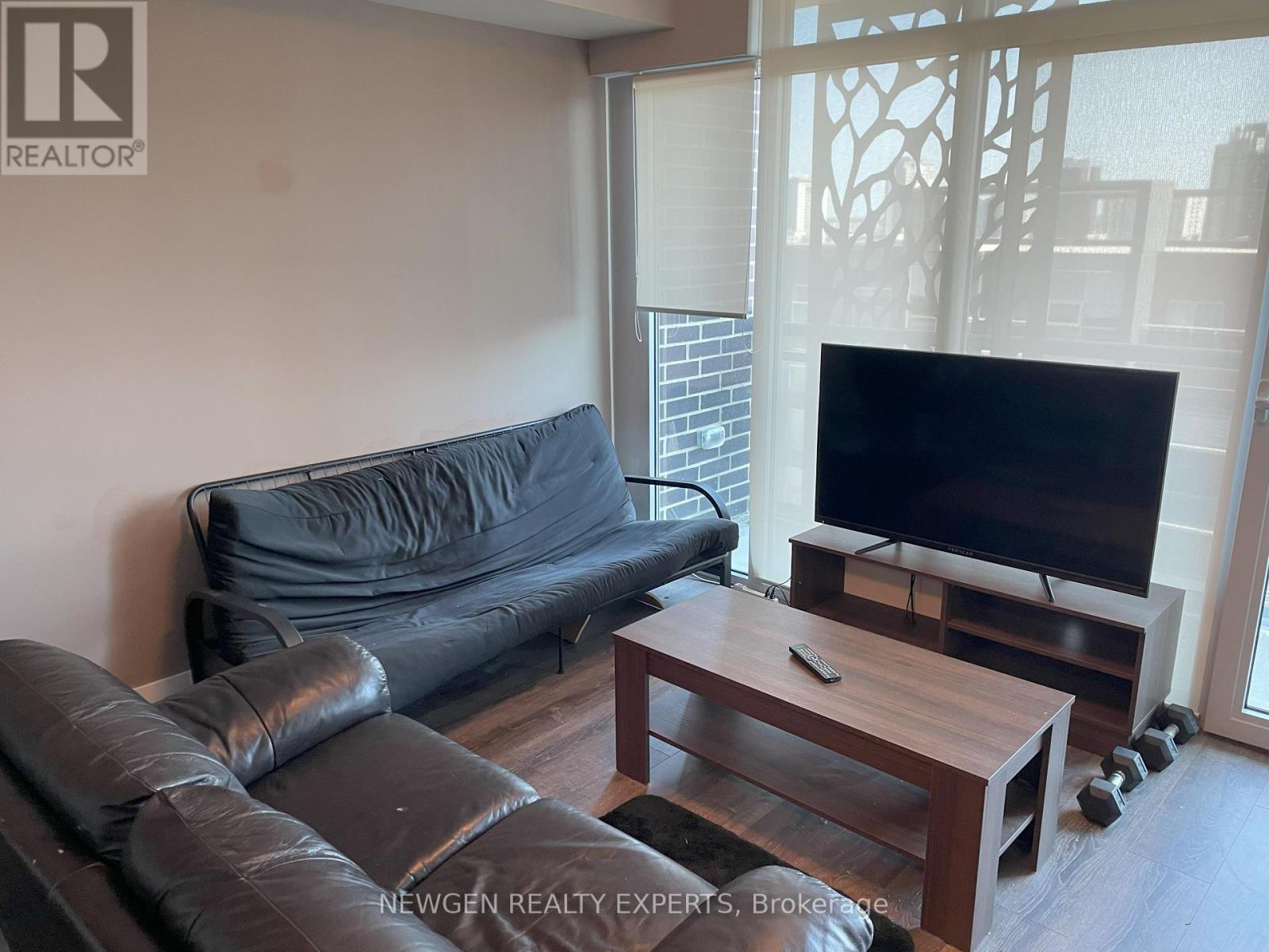 A black leather couch sits in a living room with a wooden coffee table in front of it.