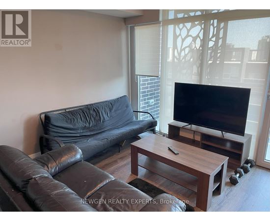 A black leather couch sits in a living room with a wooden coffee table in front of it.
