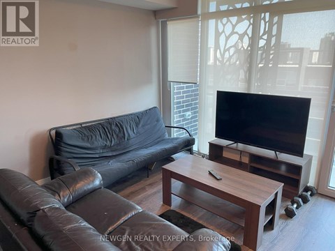 A black leather couch sits in a living room with a wooden coffee table in front of it.