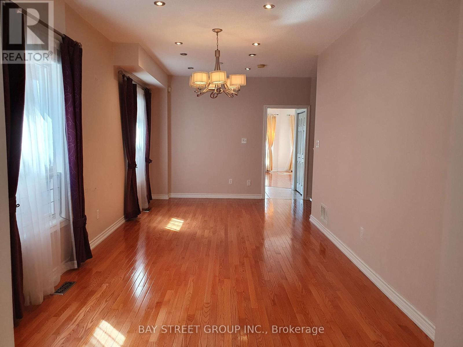 A spacious room with wooden floors and a chandelier.