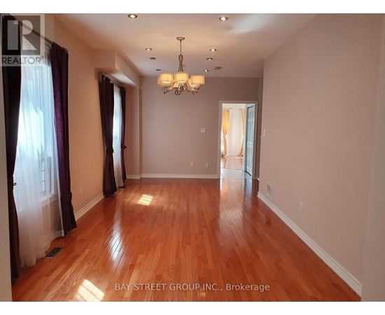 A spacious room with wooden floors and a chandelier.