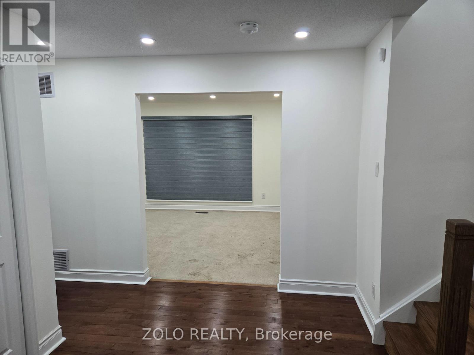 A room with a window covered by blinds and a wooden floor.
