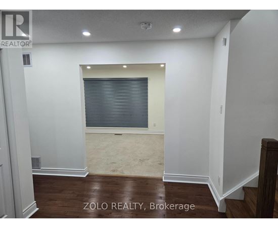 A room with a window covered by blinds and a wooden floor.