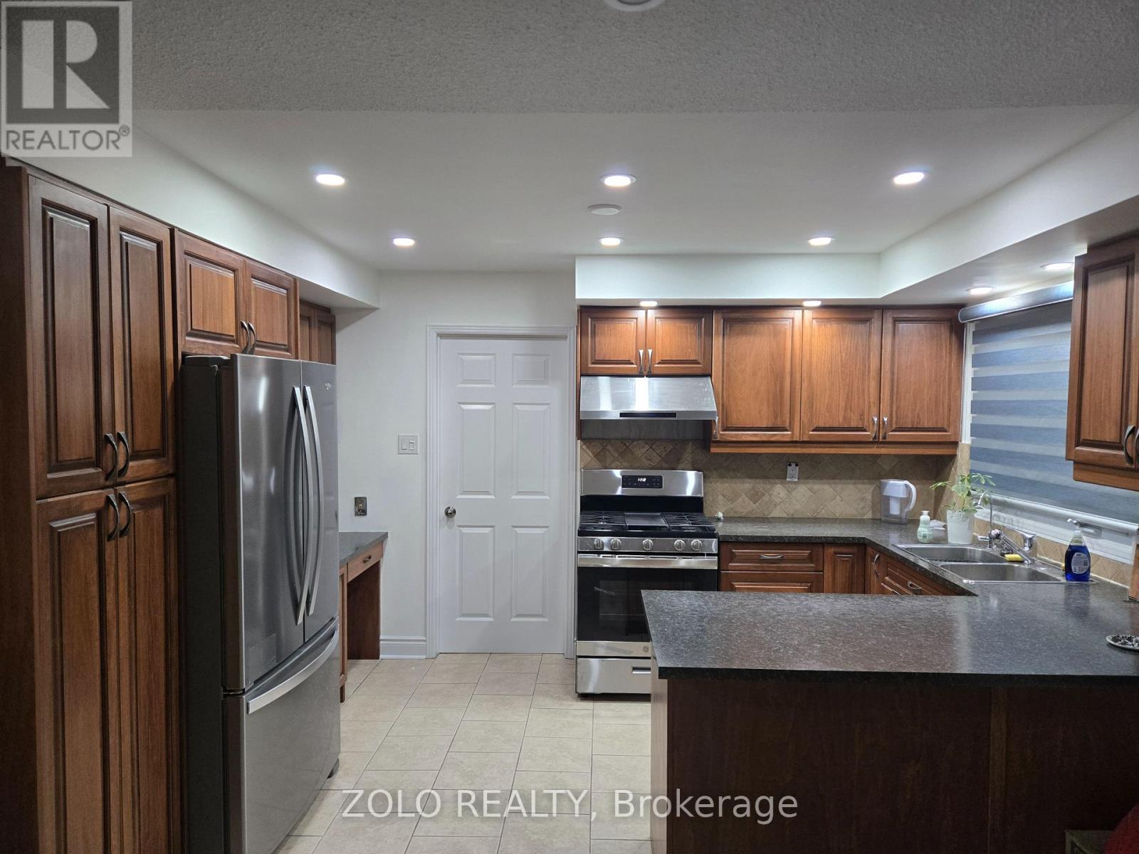 A kitchen with wooden cabinets and a stainless steel refrigerator.