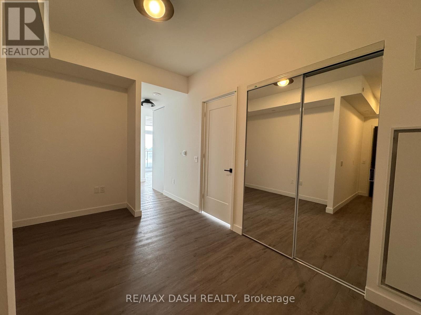 A spacious room with wooden flooring and a large mirror on the wall.