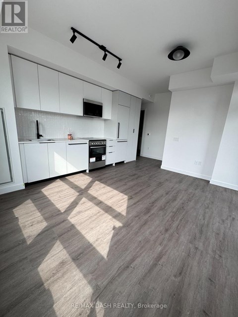 A well-lit kitchen with white cabinets and a wooden floor.
