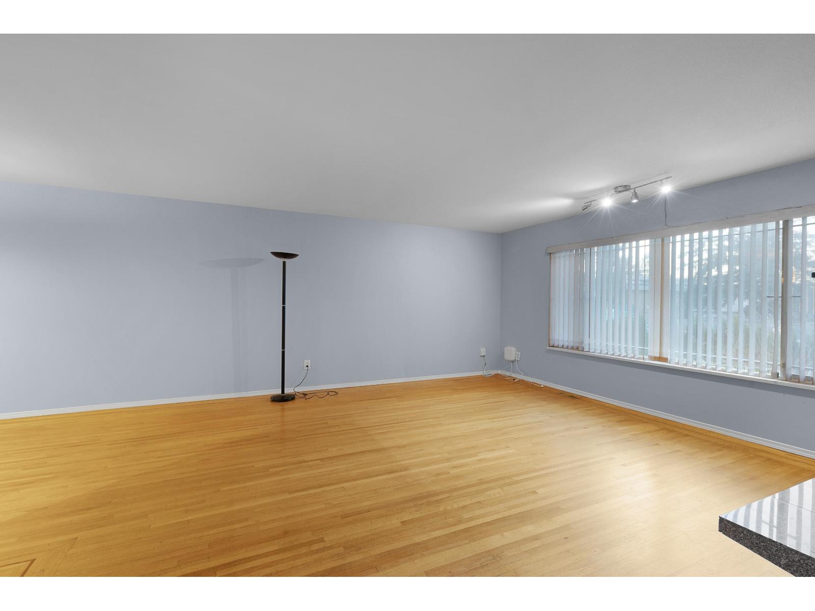 A room with wooden flooring and a black floor lamp.