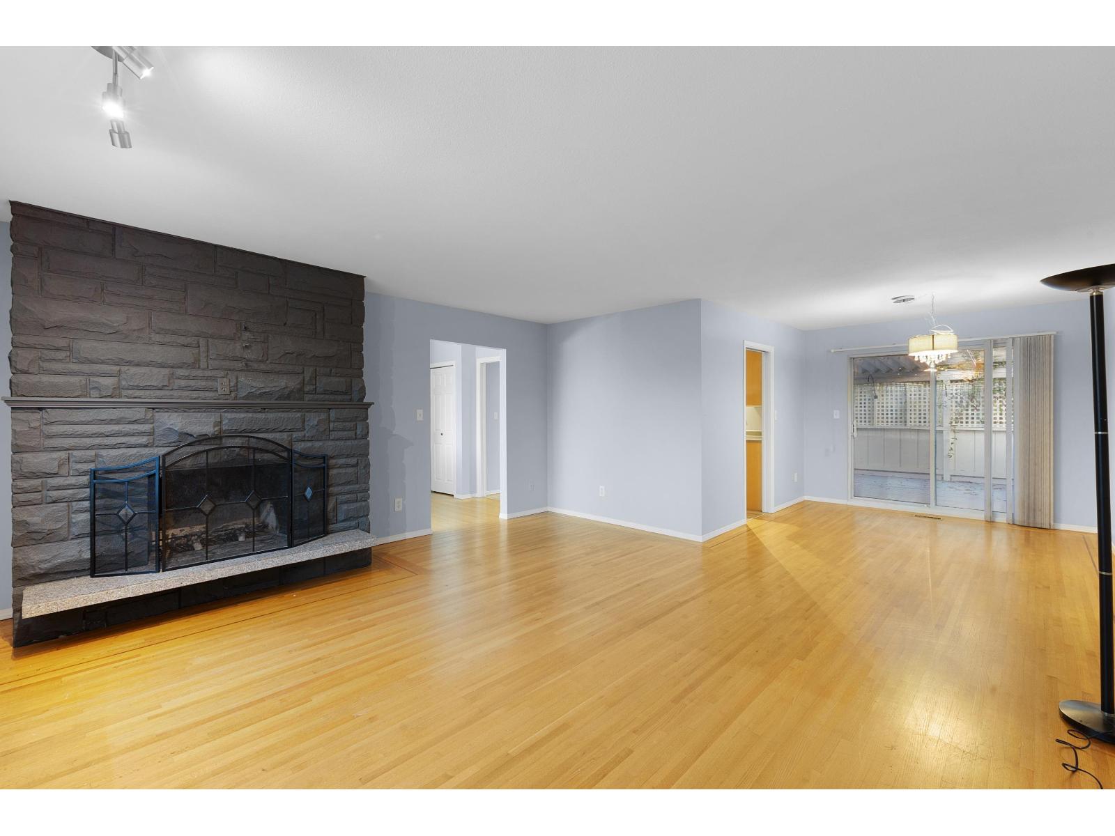 A room with a stone fireplace and wooden floors.