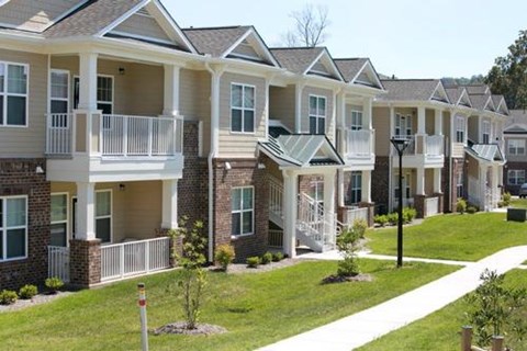 A row of townhouses with white balconies and green lawns.