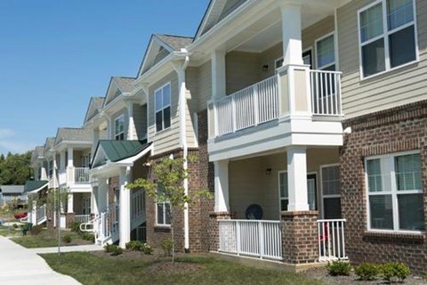 A row of townhouses with white balconies and green roofs.
