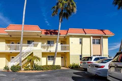 A yellow building with a red roof and a palm tree in front.